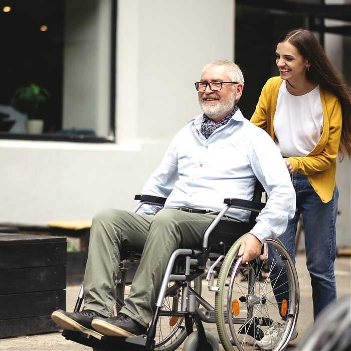 Rentner in Rollstuhl wird geschoben